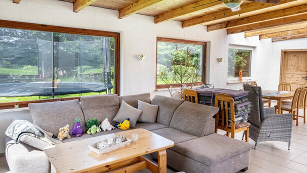 A modern living room with a sectional sofa, wooden coffee table, and a dining area with wicker chairs. - Apartment '3' with Shared Terrace, Shared Garden and Wi-Fi (Nordstrand)