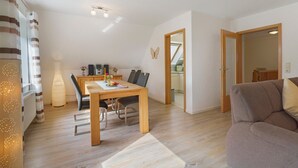 Ein modernes Wohnzimmer mit Essbereich, Holzboden und einer Couch.