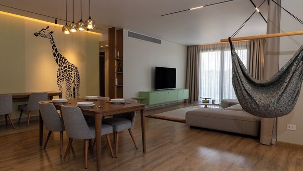 Una sala de estar moderna con comedor, un sofá, una silla colgante y un televisor.