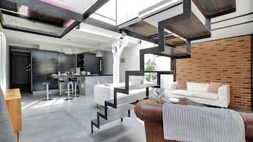 Un salon moderne avec un escalier, un coin repas et une cuisine.