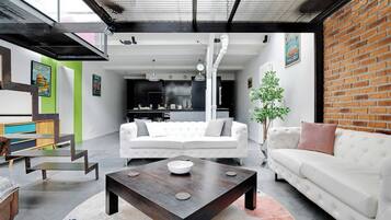 Un salon moderne avec un canapé blanc, une table basse en bois et un mur en briques.