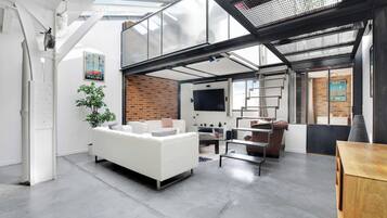 Un espace de vie moderne avec un canapé blanc, un mur en briques et une lucarne.
