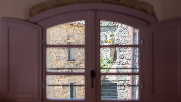 A view through a window with a stone wall and a door in the foreground.