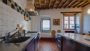 A kitchen with a tiled backsplash, stainless steel appliances, a wooden ceiling, and a window with a view.