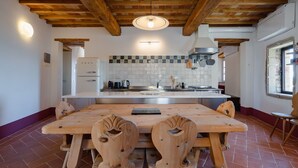 A kitchen with a wooden table and chairs, a white refrigerator, and a tiled backsplash.