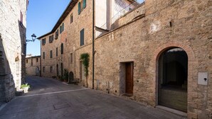 A narrow street with stone buildings, a bench, and a clear sky.