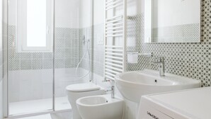 A modern bathroom with a glass shower enclosure, a toilet, a bidet, a sink, and a washing machine. - AlCastellino  holidy home Rapallo (Rapallo)
