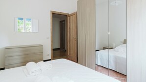 A modern bedroom with a large bed, a wooden wardrobe, and a mirror cabinet. - AlCastellino  holidy home Rapallo (Rapallo)