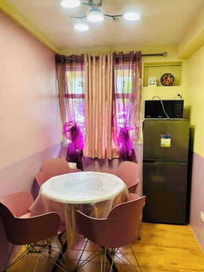 A small kitchen with a refrigerator, a microwave, and a dining table with chairs.