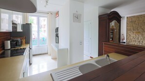 A kitchen with a stove, oven, and a sink. There is a door leading to a balcony.