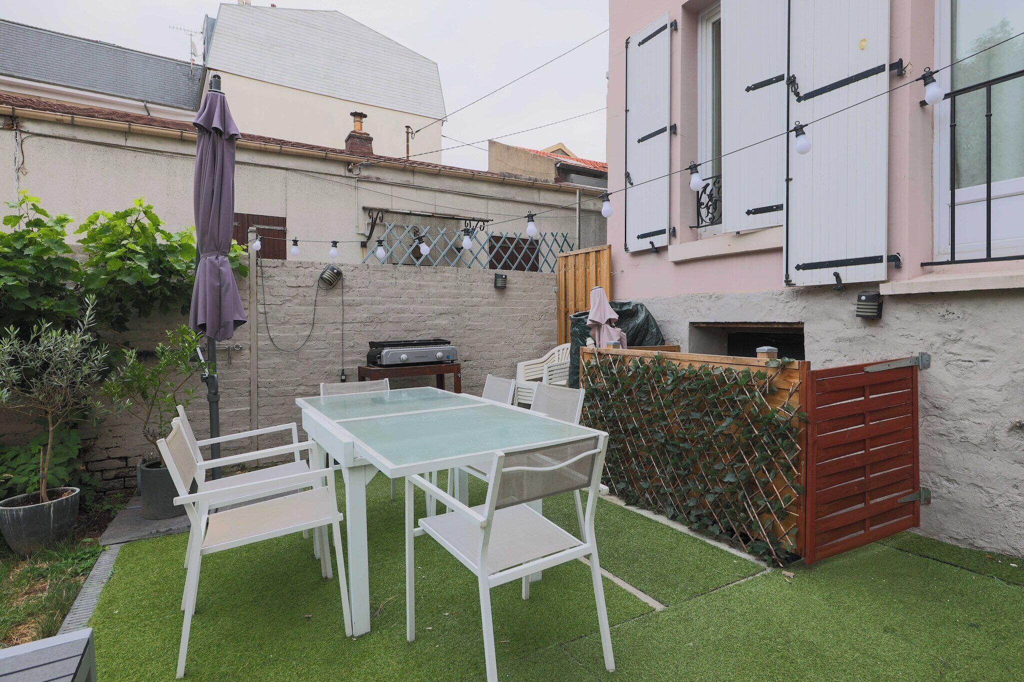 Un patio con mesa y sillas, una parrilla y un área cubierta con cerca.
