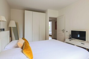 Ein Hotelzimmer mit einem Bett, einem Fernseher auf einem Tisch, einem Kleiderschrank und einer Tür zu einem weiteren Raum.