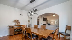 A dining area with a wooden table and chairs, a wine rack, and a hanging light fixture.