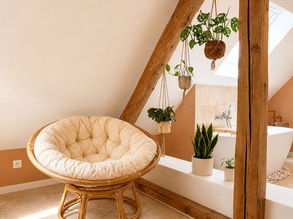 A room with a rattan chair, a bathtub, and hanging plants.