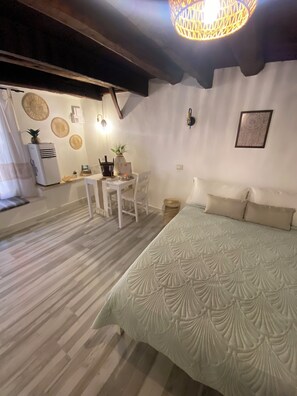 Ein Schlafzimmer mit einem Bett, einem Tisch mit Stühlen, einer Deckenleuchte und einer Wand-Klimaanlage.