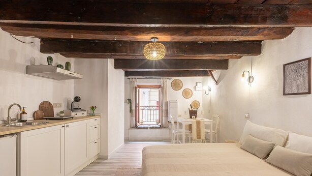Een gezellige slaapkamer met een groot bed, een houten plafond en een zithoek met een tafel en stoelen.