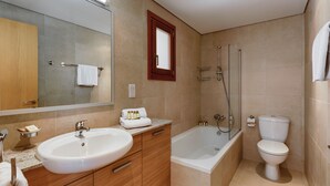 Een moderne badkamer met een wastafel, badkamermeubel, spiegel, bad en toilet.