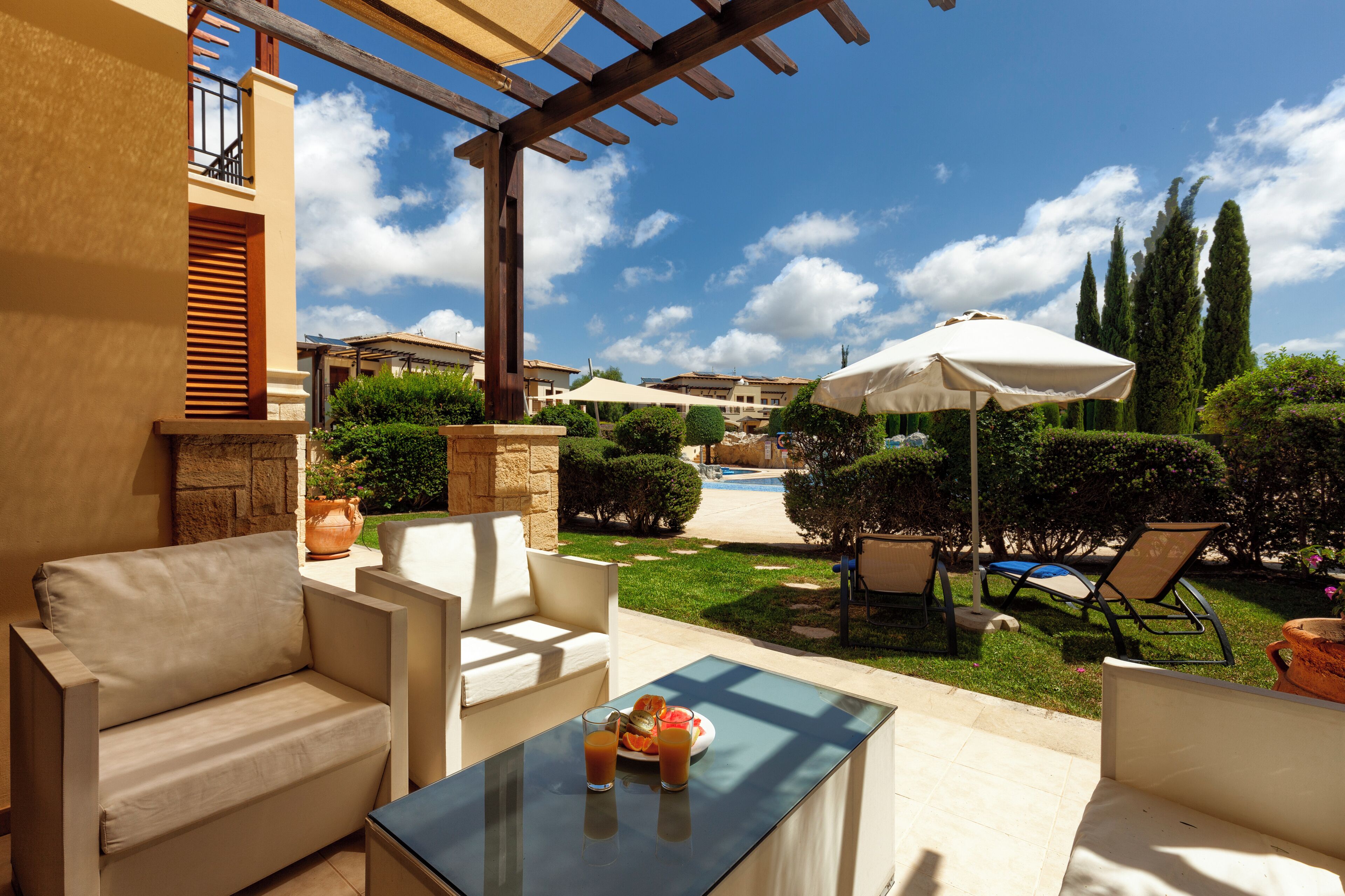 An outdoor patio area with a pool, lounge chairs, and a pergola.