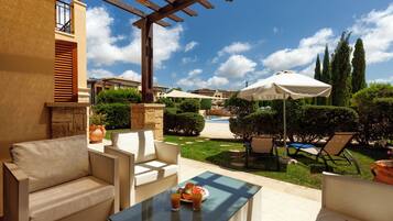 An outdoor patio area with a pool, lounge chairs, and a pergola.