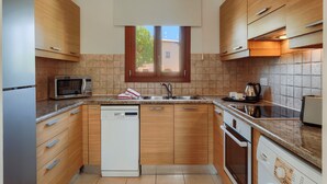 Una cuina moderna amb armaris de fusta, microones integrat, rentaplats, un rentavaixelles i una finestra amb vistes a l'exterior.