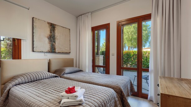 A hotel room with two beds, a large painting on the wall, and a sliding glass door leading to an outdoor area. - 2 Bedroom Apartment - CB02 (kouklia)