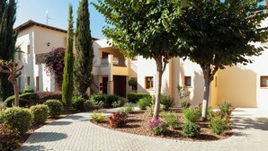 A courtyard with a paved walkway, surrounded by buildings with balconies and windows. - 2 Bedroom Apartment - CB02 (kouklia)