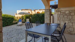 An outdoor patio with a table and chairs, surrounded by stone walls and a view of buildings in the background. - 2 Bedroom Apartment - CB02 (kouklia)