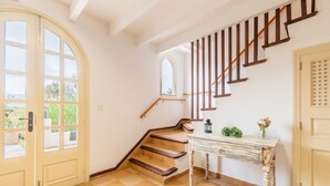 Un escalier avec des marches en bois et une rampe, une porte avec des panneaux de verre, et une petite table sur laquelle se trouvent un vase et une plante.