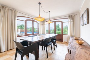Un comedor con una mesa grande, sillas y lámparas colgantes.