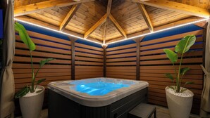 Ein Whirlpool in einem Holzraum mit schwellenartigen Wänden und Deckenbalken.