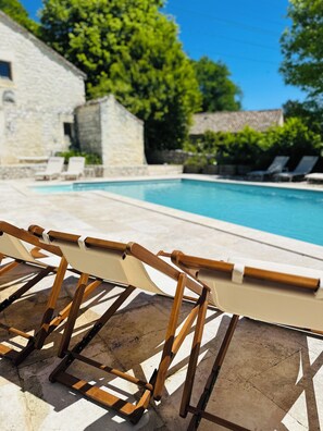 A poolside area with lounge chairs and a stone building in the background.