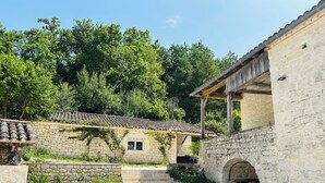 A stone building with a tiled roof, a wooden porch, and a stone staircase leading to a door. - Domaine de Péroline: Swimming pool and Jacuzzi (Cézac)