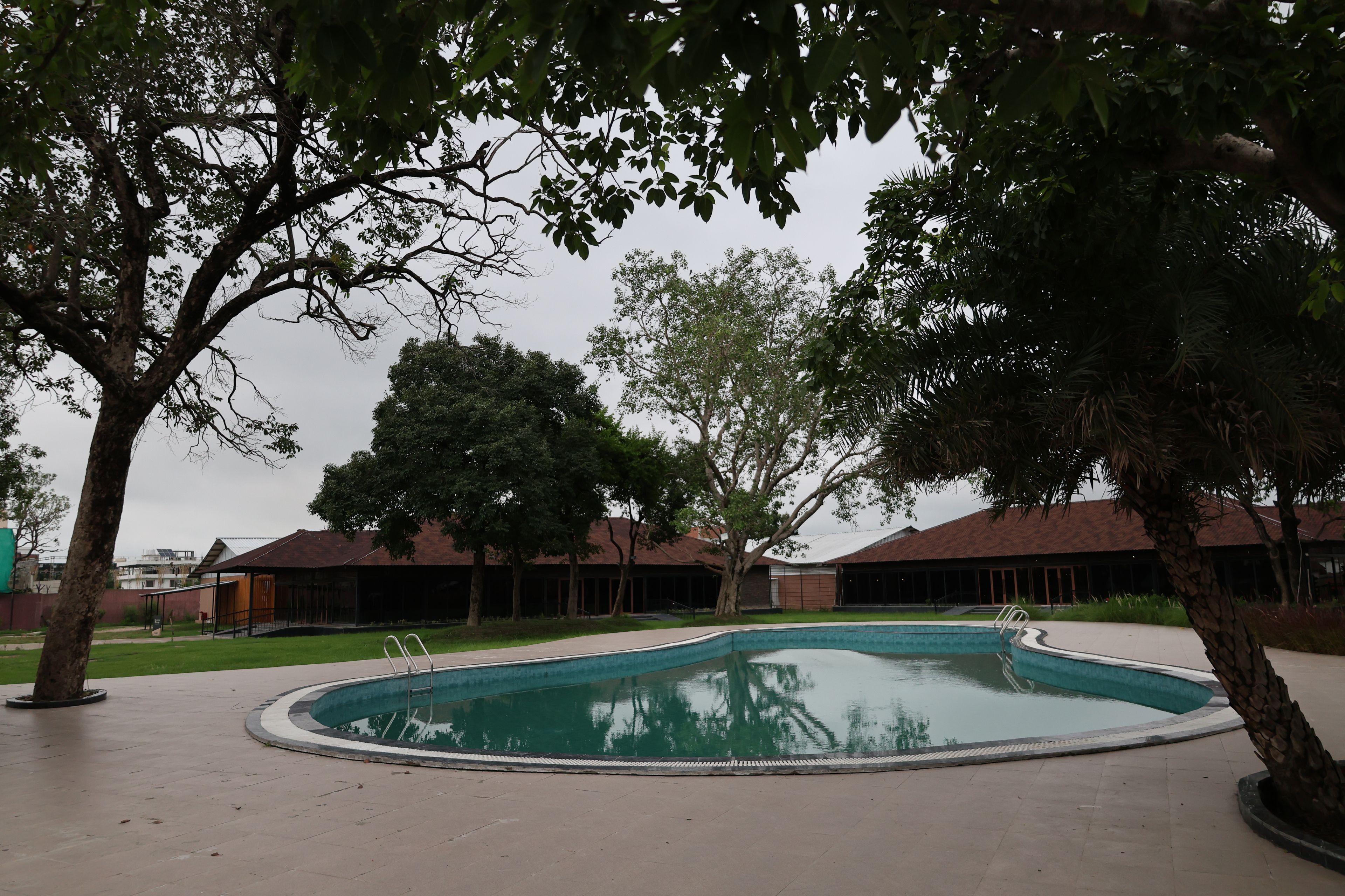 A swimming pool surrounded by trees and buildings with a flat roof.