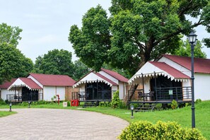 A row of white cottages with red roofs, each with a balcony and a fire extinguisher nearby.