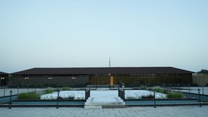 Een gebouw met een plat dak, grote ramen en een centrale ingang met treden.