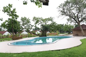 A swimming pool with a curved edge, surrounded by a paved deck.