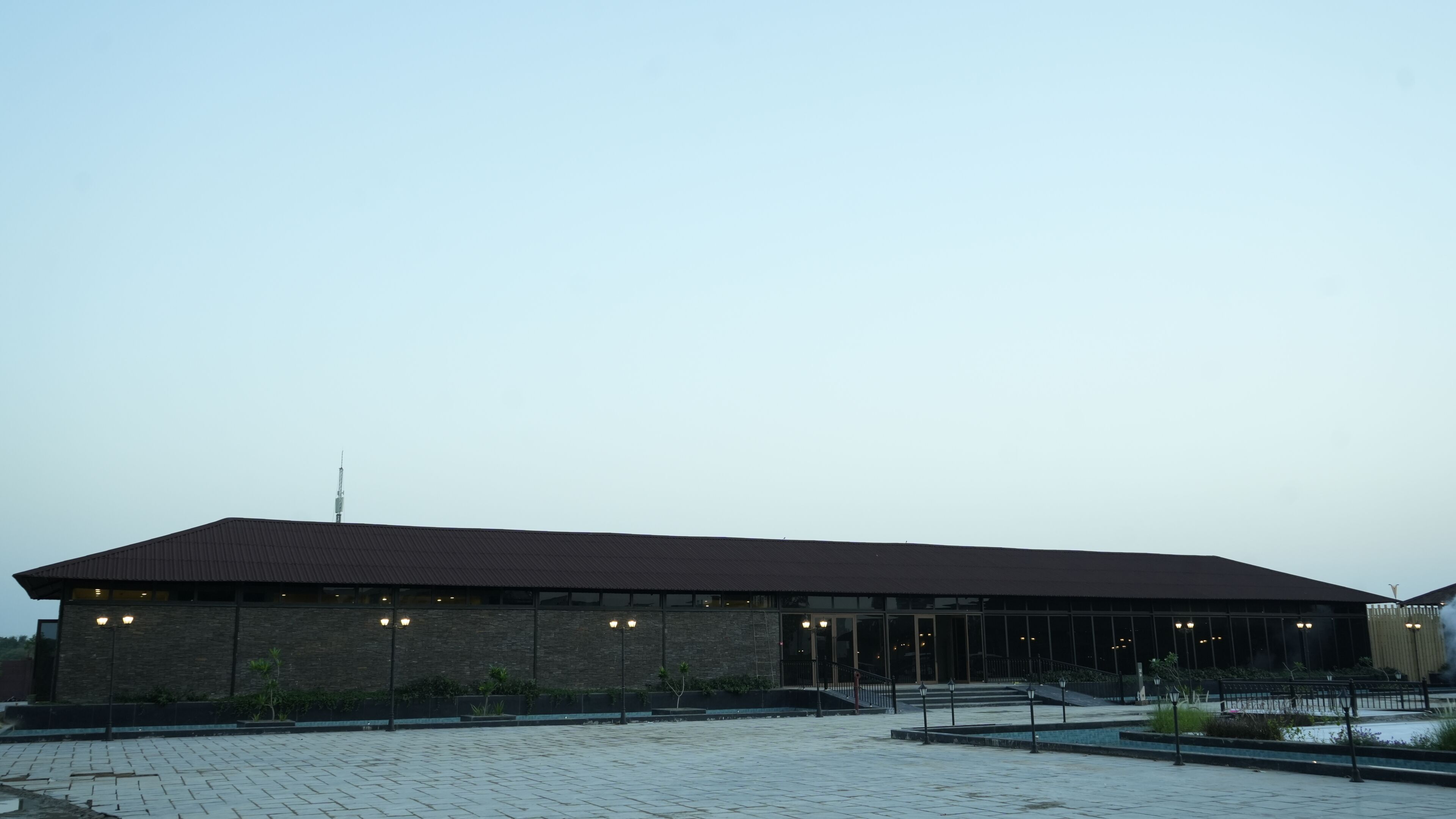 A large building with a flat roof, a brick facade, and a paved entrance area.
