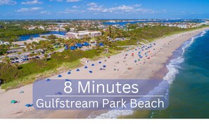 Ein Luftbild von Gulfstream Park Beach, mit blauem Himmel, zahlreichen Strandstühlen und einer Küstenlinie.