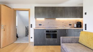A modern kitchen with dark cabinets, a built-in oven, and a coffee maker. - Apartment 'Ifinger' with Mountain View, Shared Garden and Wi-Fi (Avelengo)