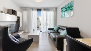Uma sala de estar moderna com sofá, cadeiras, mesa de centro e televisão.
