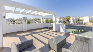 Terraço no telhado com área de estar ao ar livre, piscina e vista para edifícios próximos.