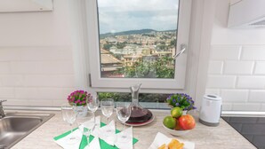 A kitchen with a view of a cityscape, a sink, a wine glass set, a fruit bowl, and a kettle. - Elegant Apartment with a Breathtaking View over the Renaissance Genoa. (Genova)