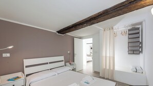 A bedroom with a bed, bedside table, and a wooden beam ceiling. - Elegant Apartment with a Breathtaking View over the Renaissance Genoa. (Genova)