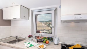 A modern kitchen with a window view, a sink, a kettle, and a pot of pasta. - Elegant Apartment with a Breathtaking View over the Renaissance Genoa. (Genova)