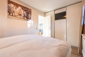 A hotel room with a large bed, a wardrobe, and a door leading to a balcony. - Käpt'n 25 - Käpt'n 25 Westerland (Sylt)