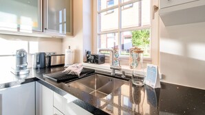 A modern kitchen with a black countertop, stainless steel appliances, and a window with a view of a building. - Käpt'n 25 - Käpt'n 25 Westerland (Sylt)