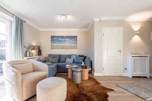 A modern living room with a sofa, ottoman, and a rug.
