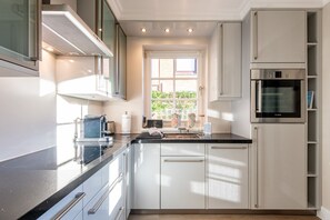 Una cocina moderna con armarios blancos, encimera negra y horno Bosch.