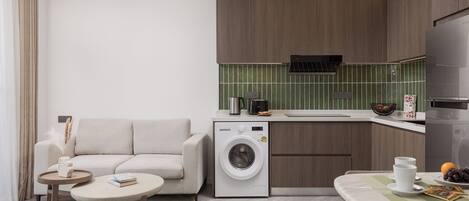 Una cocina moderna con lavadora integrada, un comedor con mesa y sillas, y una sala de estar con sofá.
