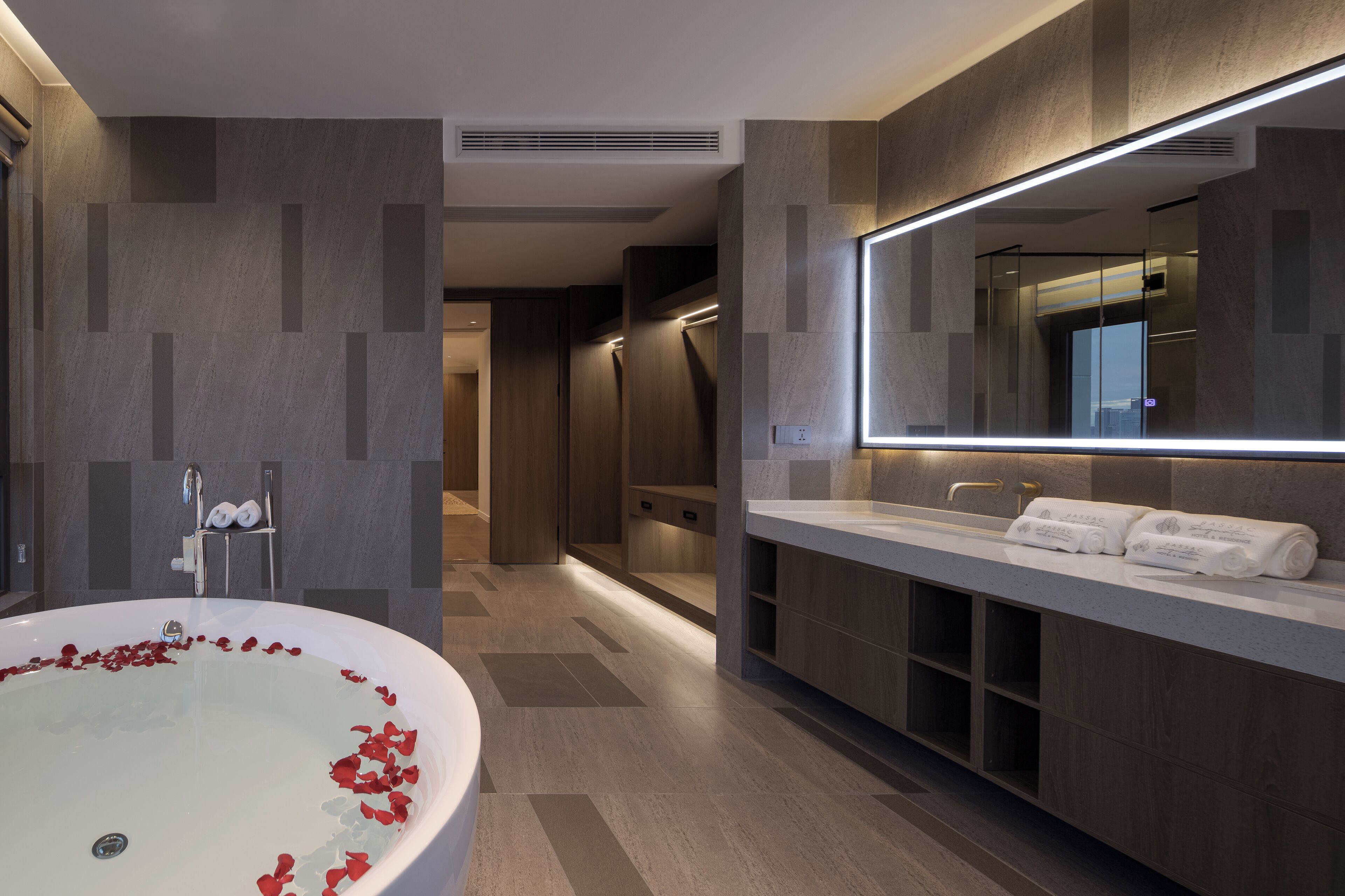A modern bathroom with a large bathtub, a vanity with a mirror, and a shower area.